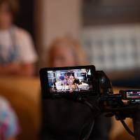 camera close-up of students and Shelley Irwin, WGVU host, on a yellow couch